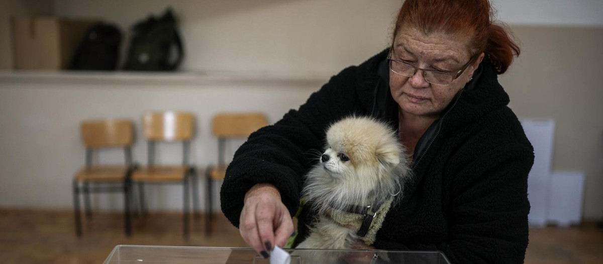 SOFIA (Bulgaria), 25/10/2026.- A woman holding a dog casts her ballot during the first round of the presidential election in Sofia, Bulgaria, 25 October 2026. Nearly 6.6 million eligible voters are called to the polls to elect Bulgarias next president in the first round of voting. (Elecciones) EFE/EPA/BORISLAV TROSHEV
