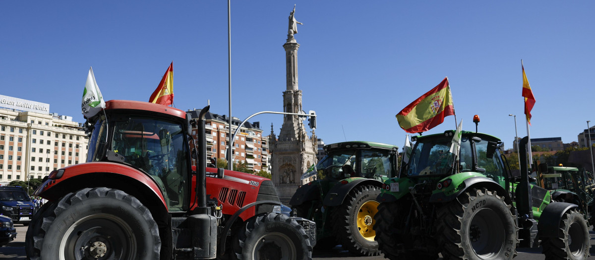 Los tractores pasan ante la estatua de Colón en Madrid durante la protesta aplazada de los agricultores y ganaderos