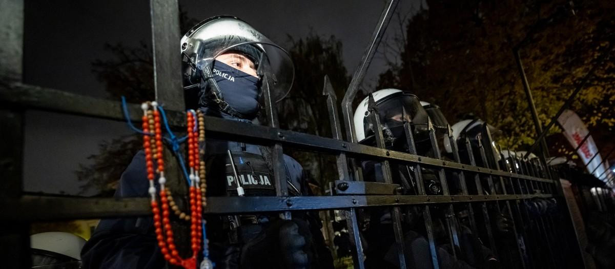 Agentes de policía permanecen tras una valla mientras los manifestantes se reúnen ante la sede del Tribunal Constitucional de Polonia