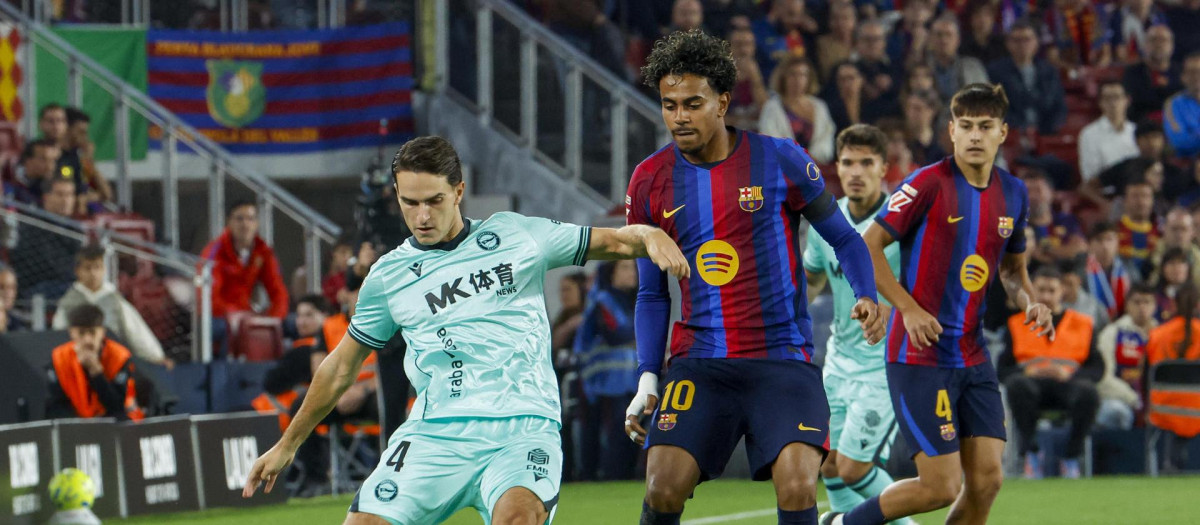 Denis Suárez (i) juega un balón ante Lamine Yamal (2-i) durante el Barça - Alavés