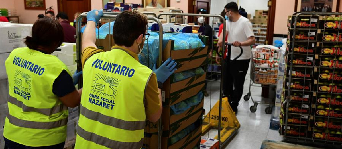 Varios voluntarios preparan lotes de alimentos para personas necesitadas en la sede de la obra social Nazaret, en el barrio obrero de San Blas