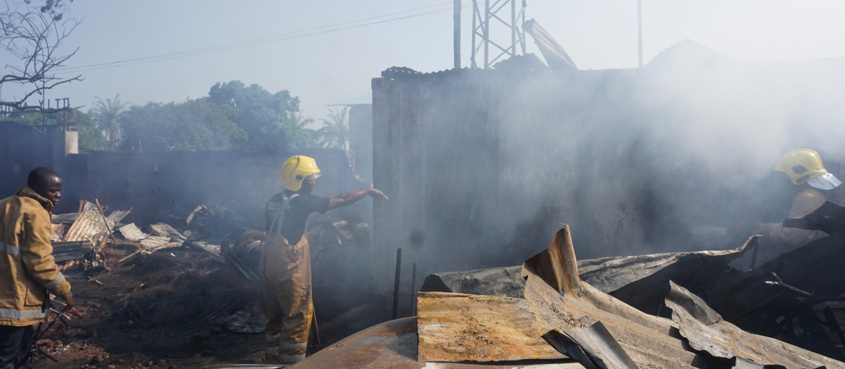 Los bomberos trabajan junto a los restos quemados de la explosión en Freetown