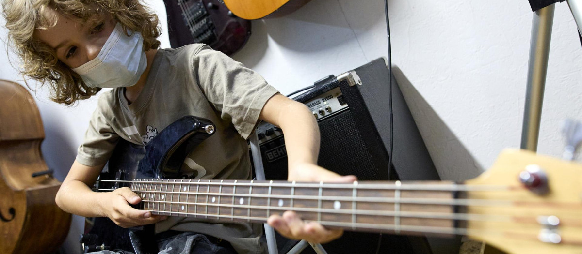 Un niño tocando el bajo en un campamento urbano artístico en Madrid