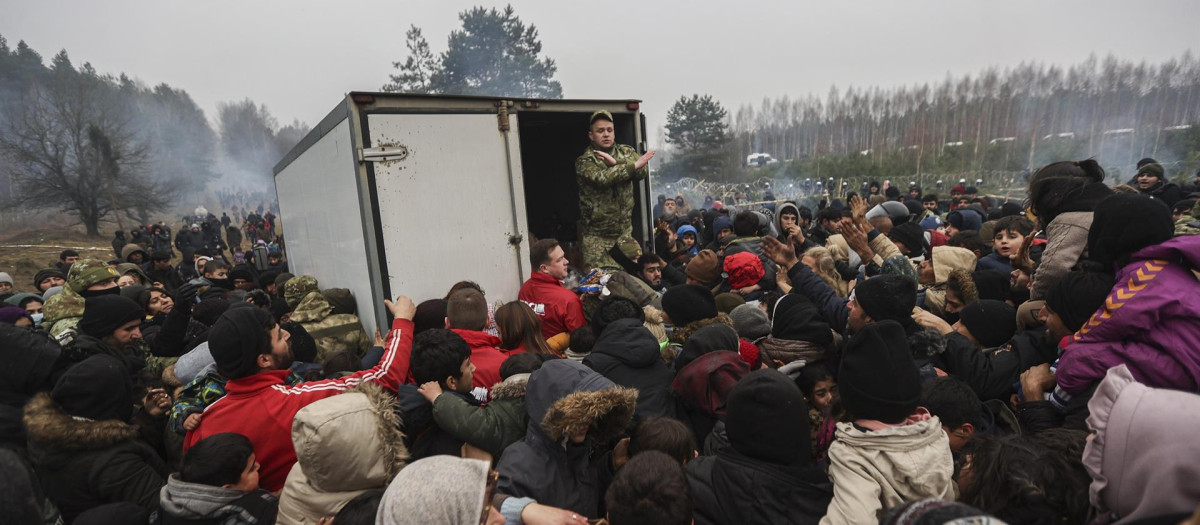 Inmigrantes se reúnen para obtener ayuda humanitaria difundida por militares bielorrusos en el campamento en la frontera entre Bielorrusia y Polonia en la región de Grodno