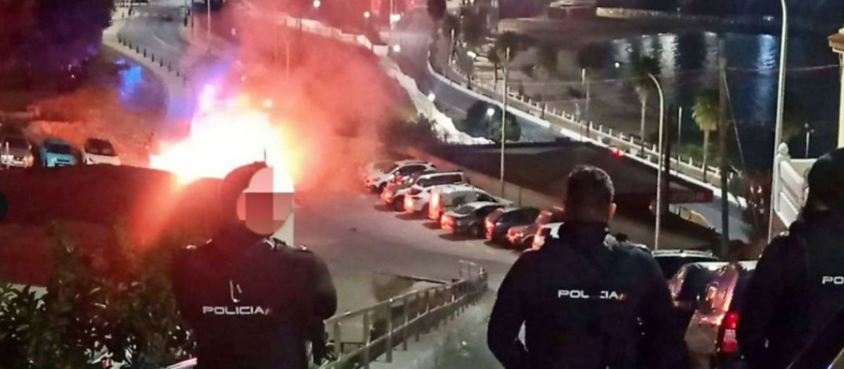 Agentes de la Policía Nacional observan un contenedor ardiendo en Ceuta