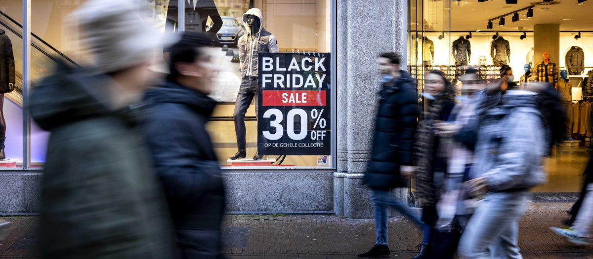 Viandantes pasan delante de un establecimiento con ofertas de Black Friday en Ámsterdam