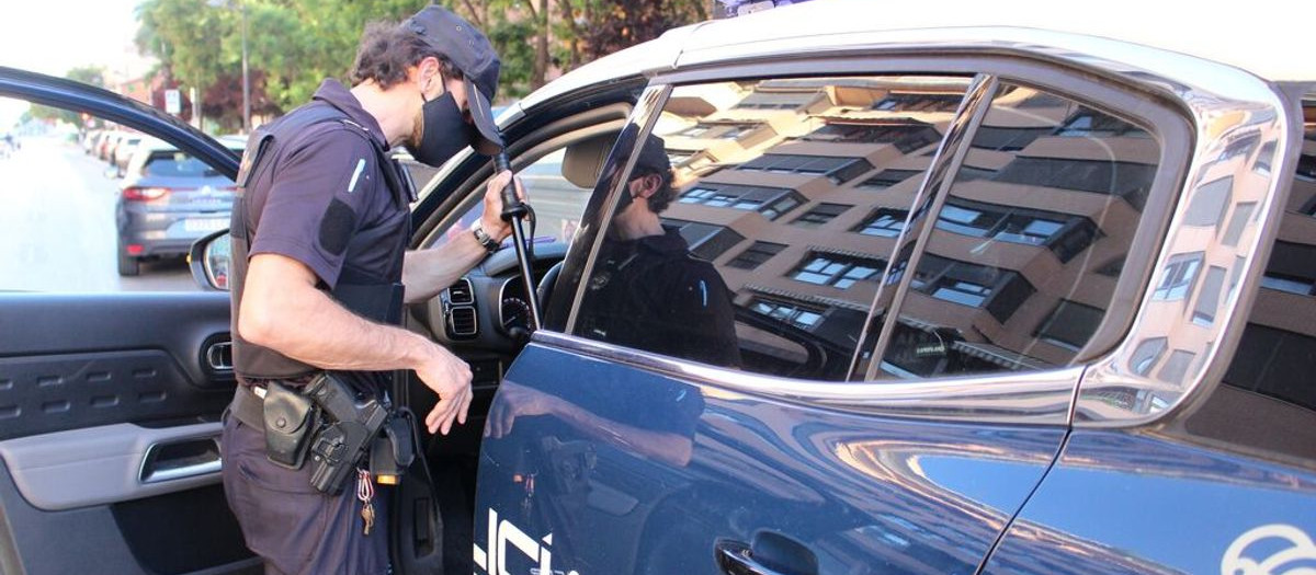 Un agente junto a un coche patrulla