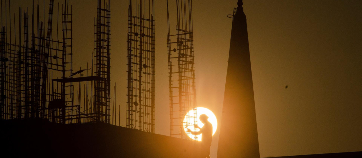 La sombra de un trabajador indio aparece silueteada frente al sol este lunes en unas obras en la ciudad de Chennai, India