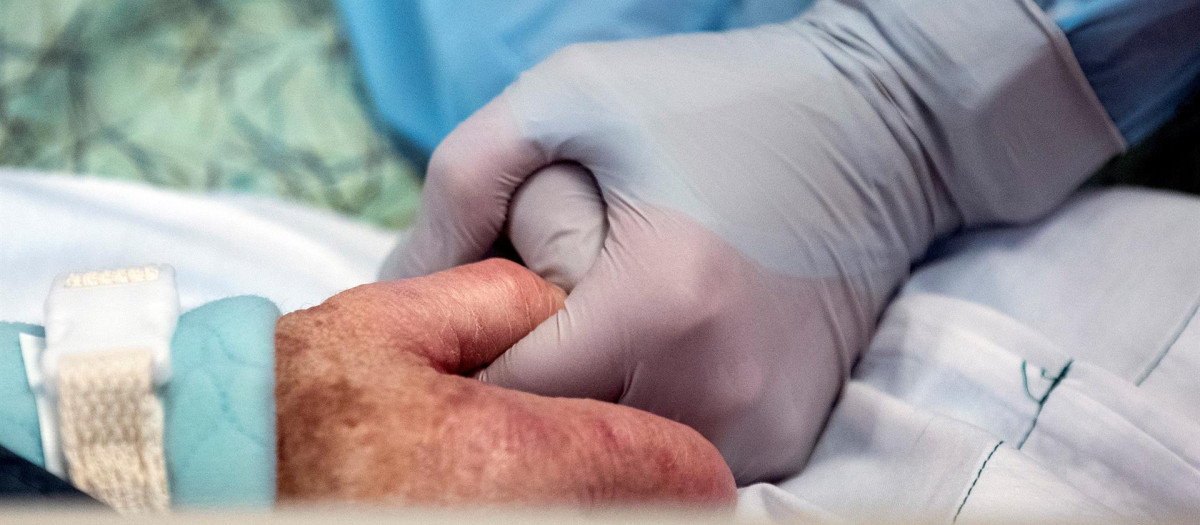 Una enfermera coge la mano de una paciente con coronavirus que está ingresada en la UCI del Hospital de Sharp Grossmont en La Mesa, San Diego, California, Estados Unidos