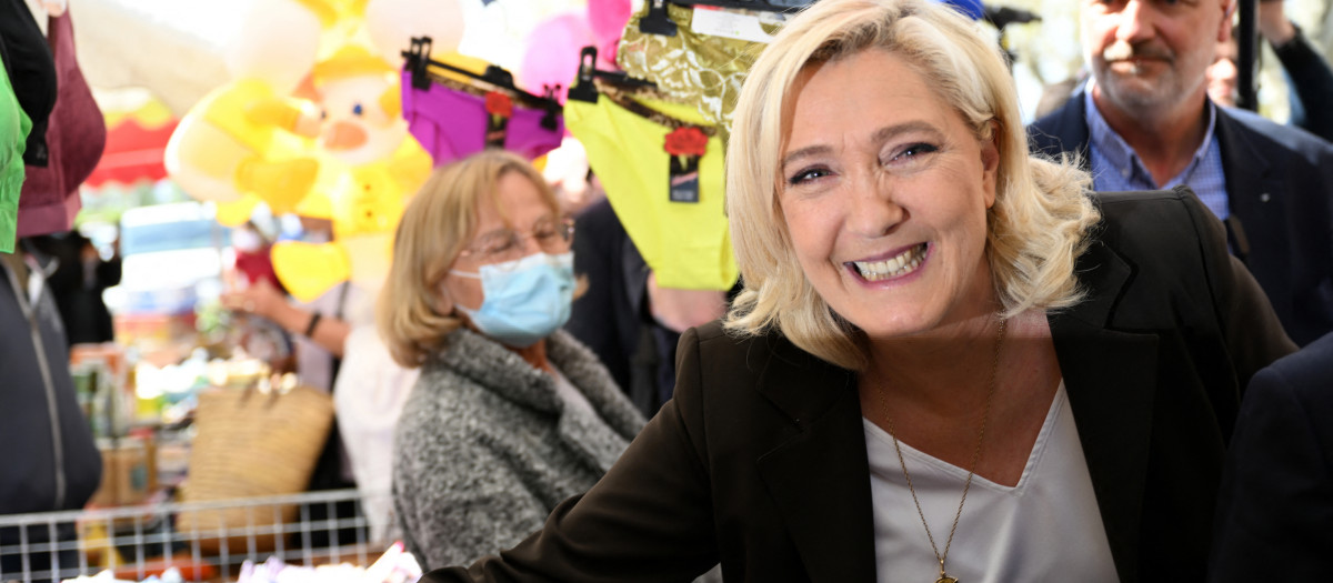 French far-right party Rassemblement National (RN) presidential candidate Marine Le Pen (R)  shakes hands with a supporter during a campaign visit at Pertuis' market, South of France, on April 15, 2022. - Marine Le Pen will face French President and liberal party La Republique en Marche (LREM) candidate for re-election Emmanuel Macron in a run-off vote on April 24, 2022, after first round voting on April 10. (Photo by CHRISTOPHE SIMON / AFP)