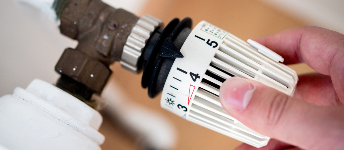 Un hombre baja la temperatura de la calefacción en su vivienda