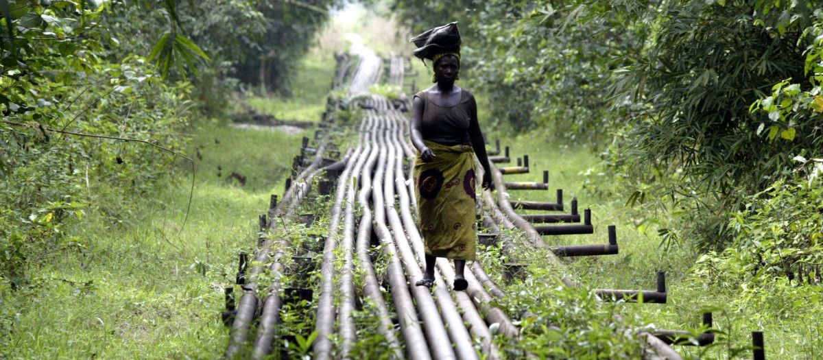 Una mujer camina a lo largo de un gasoducto cerca de la estación de flujo Utorogu de Shell en Warri, Nigeria