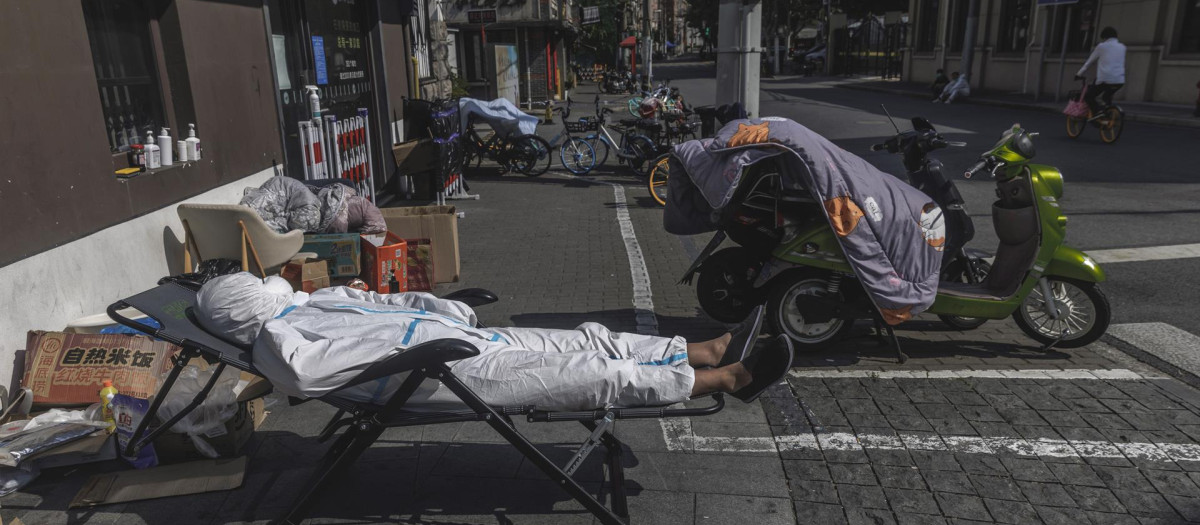 Un repartidor con equipo de protección duerme la siesta en la calle en medio del confinamiento