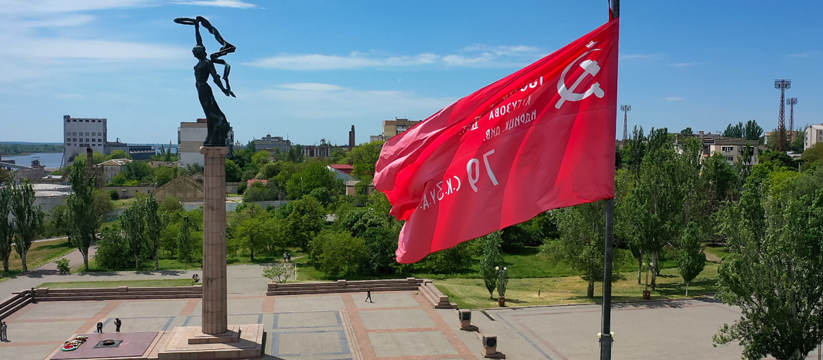 Una réplica de la bandera soviética de la victoria vuela junto a un monumento conmemorativo de la Segunda Guerra Mundial en la ciudad de Jersón el 20 de mayo de 2022, en medio de la acción militar rusa en curso en Ucrania