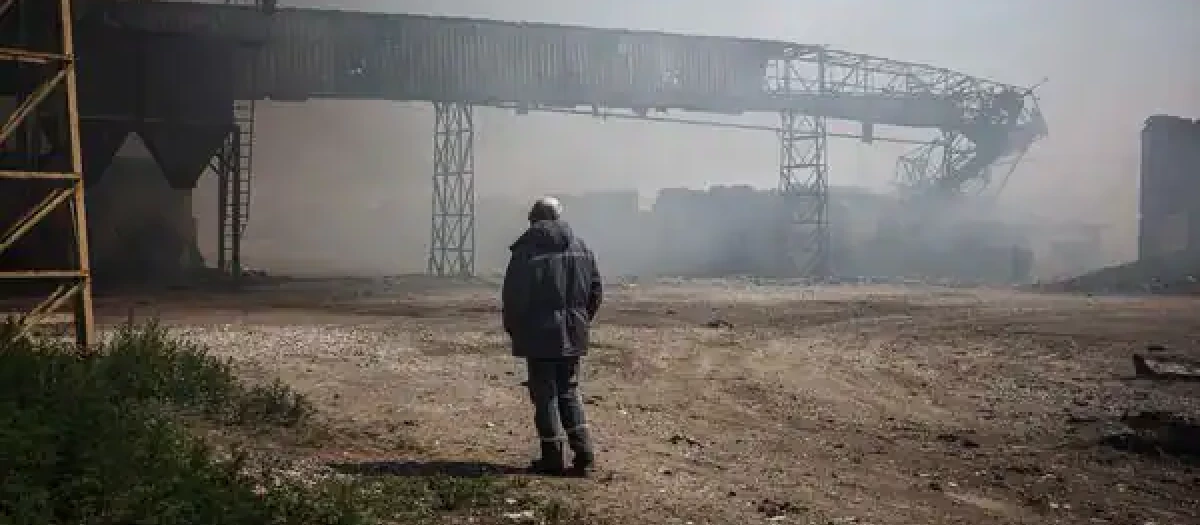 Un hombre observa como se eleva el humo de unos silos calcinados