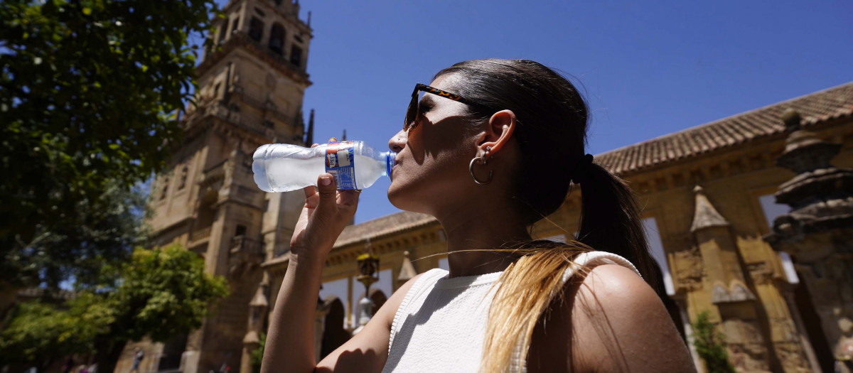 Una joven bebe agua para refrescarse en el Patio de los Naranjos de Córdoba