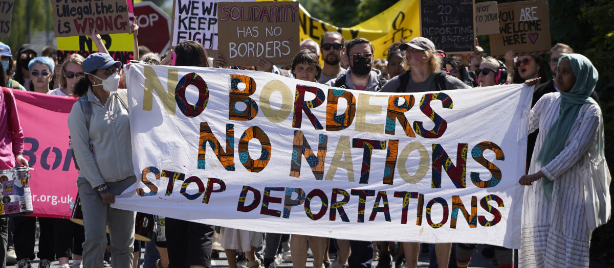 Durante una manifestación contra la deportación de inmigrantes ilegales a Ruanda, un cártel reza: "sin fronteras ni naciones, parad las deportaciones"