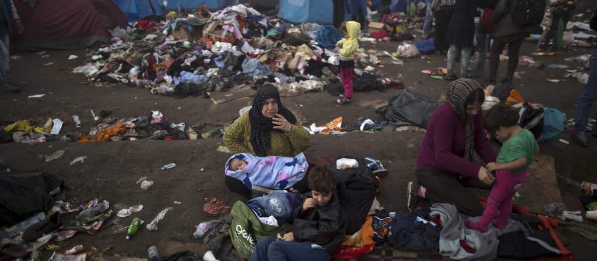 Syrian refugee Sarah Ali, 53, center, holds her grandson Jood, 2 months, while she and other members of her family rest on the ground near a makeshift camp for asylum seekers, after crossing the Serbian-Hungarian border near Roszke, southern Hungary, Saturday, Sept. 12, 2015.