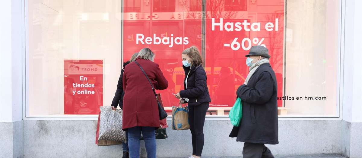 Varias personas pasan delante de un escaparate durante las rebajas de enero