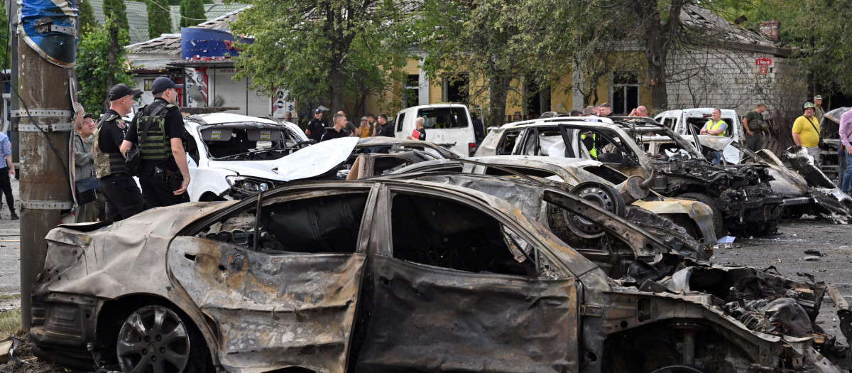 Police officers stand beside charred cars following a Russian airstrike in the city of Vinnytsia, west-central Ukraine, on July 14, 2022. - Russian missiles struck Vinnytsia, a city in central Ukraine hundreds of kilometres from the front lines, on July 14, killing at least 23 people including three children. (Photo by Sergei SUPINSKY / AFP)