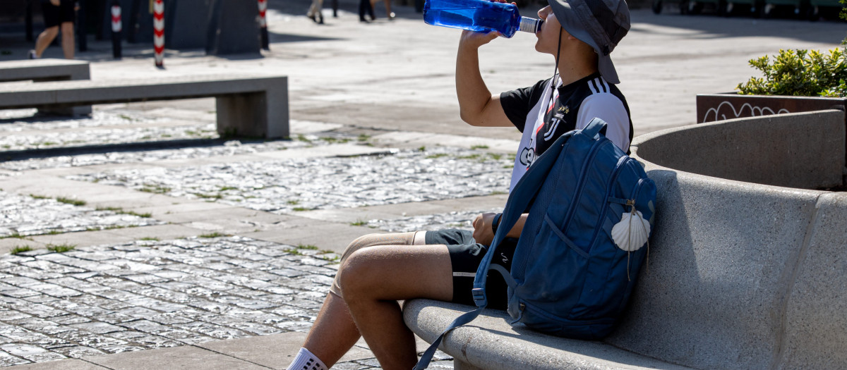 Un peregrino bebe agua en la plaza del Mercado de Logroño