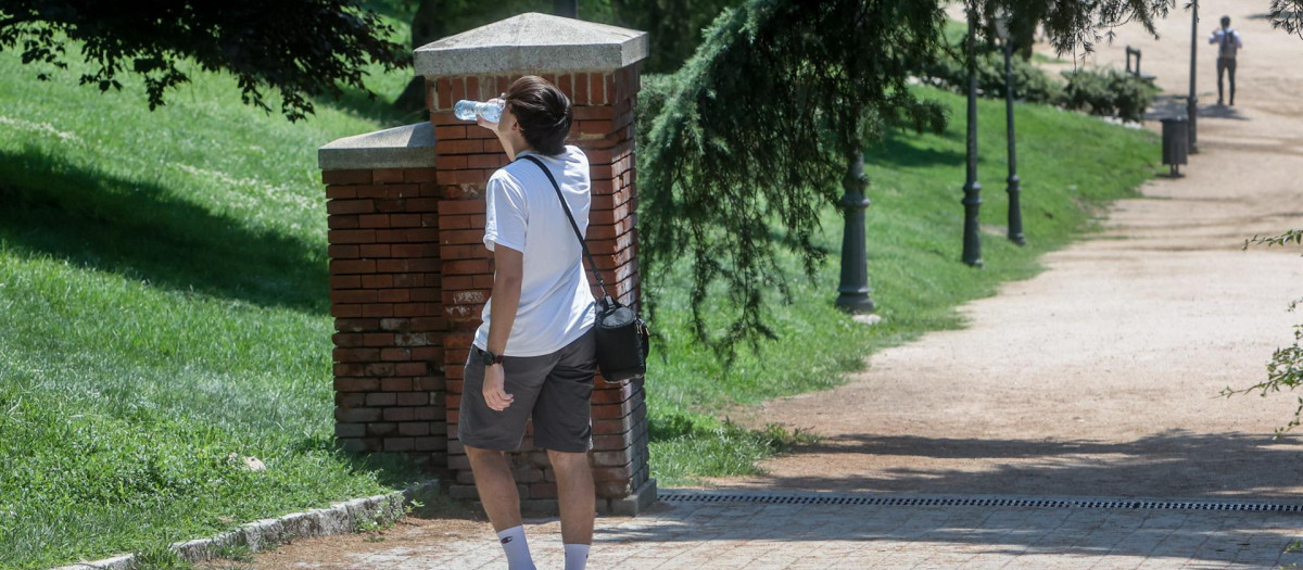 Un joven bebe agua mientras realiza un paseo