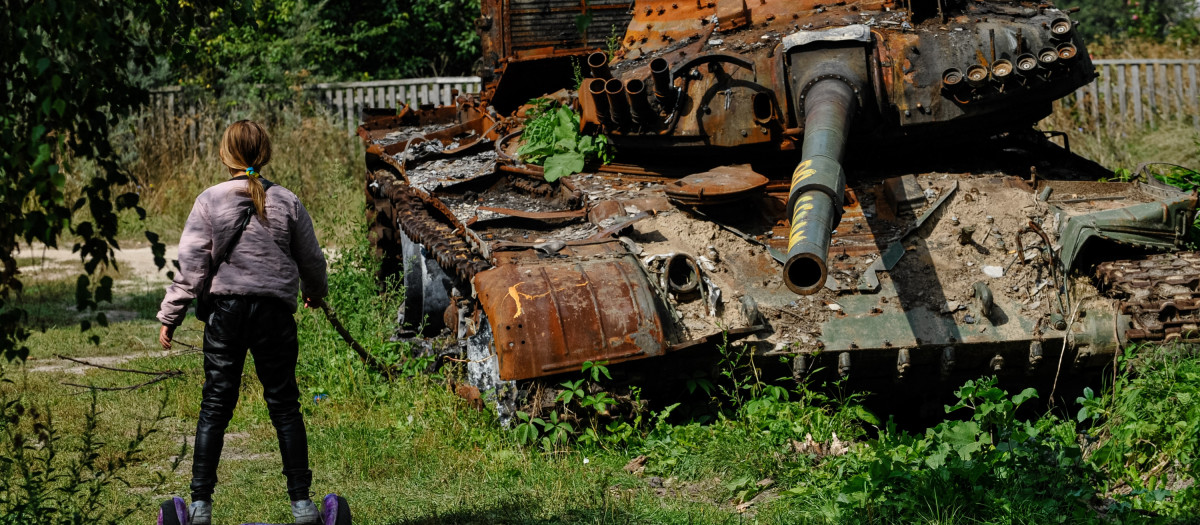 Una niña ucraniana juega cerca de los restos de un tanque de guerra