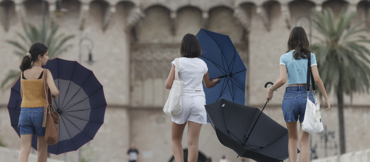 Varias chicas con sus paraguas frente a las torres de Serrano de Valencia