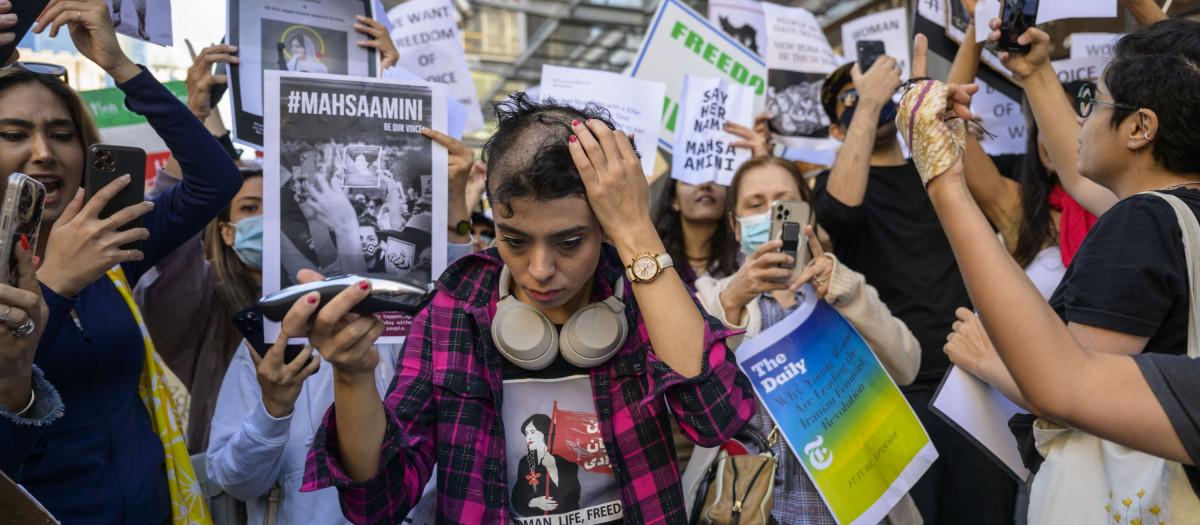 Activist Forouzan Farahani shaves her head in protest over the death of Mahsa Amini in Iran outside The New York Times building in New York City on September 27, 2022. - More than 75 people have been killed in the Iranian authorities' crackdown against unrest sparked by the death of Kurdish woman Mahsa Amini in morality police custody, a rights group said on September 26. (Photo by ANGELA WEISS / AFP)