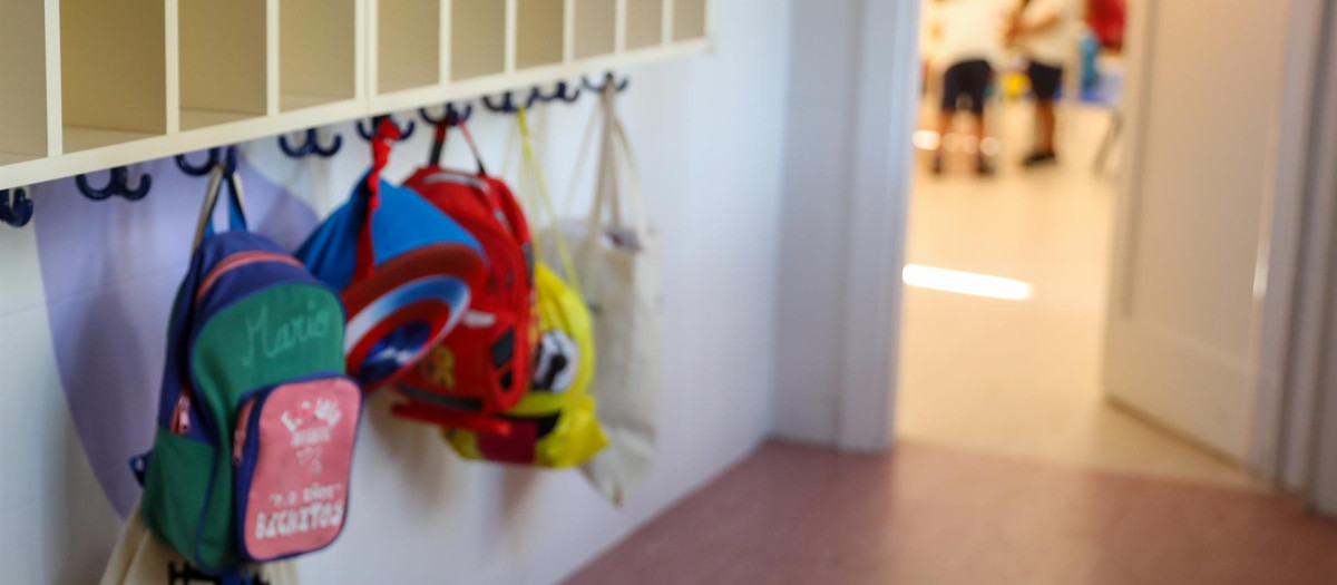 Varias mochilas en una percha de un aula