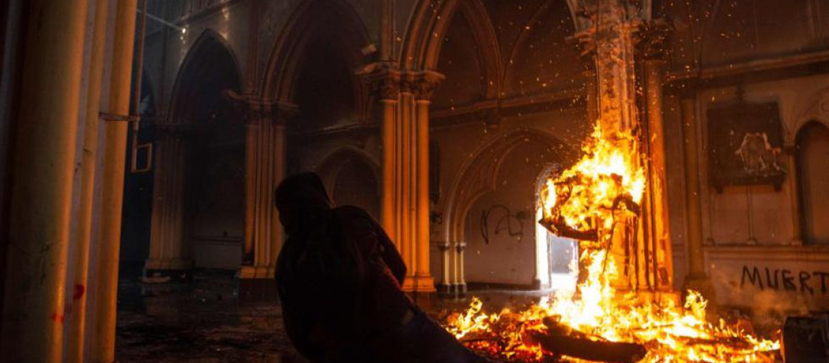 Un manifestante prende fuego dentro de la iglesia de San Francisco de Borja durante enfrentamientos con la policía antidisturbios en la conmemoración del primer aniversario del levantamiento social en Chile