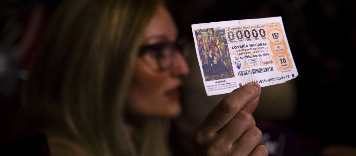 Una mujer muestra su décimo premiado con el número 00000 en 2014