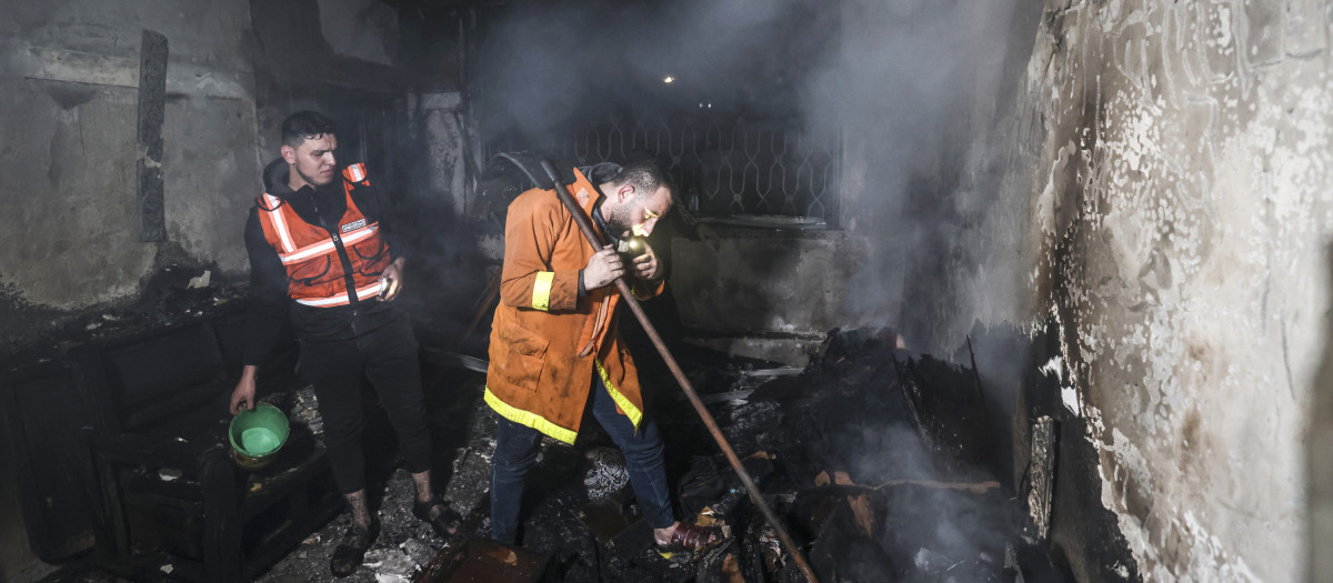 Bomberos palestinos apagan las llamas en un departamento devastado por el fuego en el campo de refugiados de Jabalia