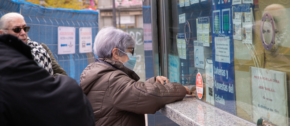 Una mujer compra un décimo de lotería en una administración