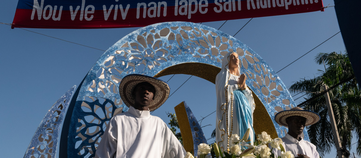 «Liberación», corearon estos fieles entre los cuales muchas de las mujeres vestían camisetas estampadas con la efigie de la Virgen recordando que los hijos de María nunca pierden la batalla. La marcha se extendió por varias horas en una capital que lucha por mantenerse a flote en un país sin garantías. Con banderas azules y rojas a lo largo de la ruta había pancartas que pedían el establecimiento de la paz. «Queremos vivir en paz, sin secuestros», se leía en una de las pancartas. Muchos de los que veneraban lo hicieron con atuendos azules. Durante la procesión se escuchó música y cánticos alusivos a la Virgen María. «Jesús, perdónalos, porque no saben lo que hacen», también se escuchó clamar a los católicos, mientras varias personas agradecían a la Virgen María por haber escuchado sus oraciones. Rezos y cantos matizaron el recorrido de esta tradicional marcha realizada en un contexto de precaria seguridad. La fiesta de la Inmaculada Concepción se celebra cada 8 de diciembre en varias ciudades de Haití por fieles católicos. Durante los últimos cuatro años la marcha se ha referido a la crisis que abate al país, con reclamos en las pancartas y comentarios políticos. Haití enfrenta una grave crisis económica, social y humanitaria, agravada por el accionar de las bandas armadas que dominan a su antoja grandes extensiones de territorio de Puerto Príncipe y algunas otras zonas del país.