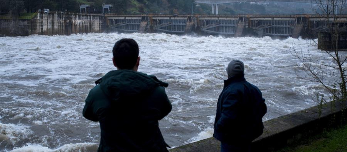 Dos hombres observan la fuerza del Miño a su paso por el embalse de Velle, en Orense