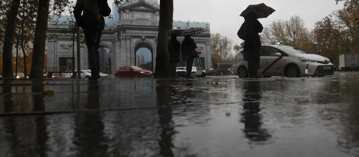 Varias personas se protegen con el paraguas de la lluvia en Madrid