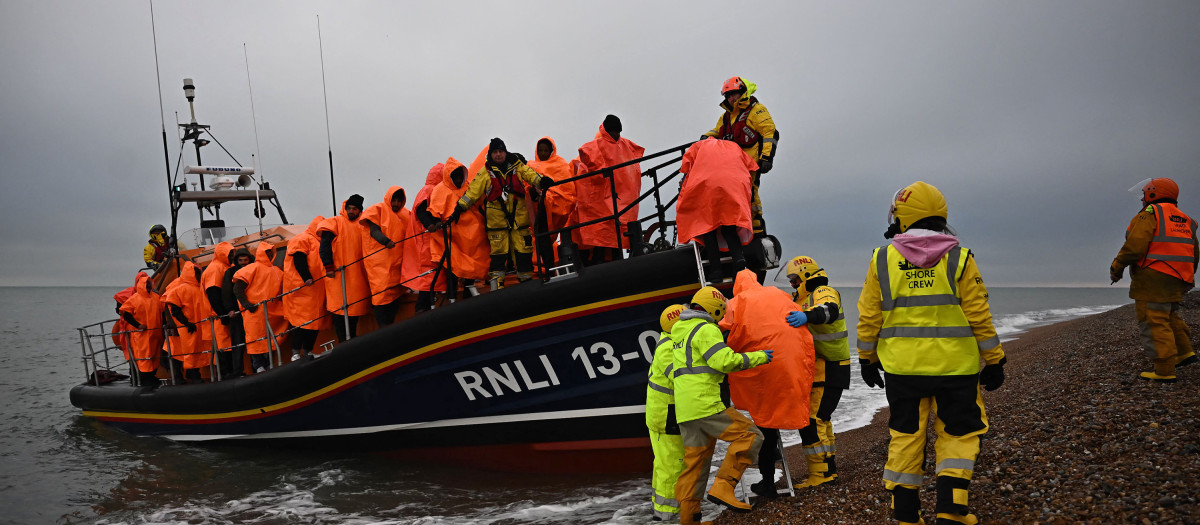 (FILES) In this file photo taken on December 9, 2022 migrants, picked up at sea attempting to cross the English Channel, are helped ashore from an Royal National Lifeboat Institution (RNLI) lifeboat, at Dungeness on the southeast coast of England. - UK high court judges ruled, on December 19, 2022 that the British government's controversial plan to deport migrants to Rwanda is lawful, after flights were thwarted through legal challenges by charities and asylum-seekers. In a bid to deal with the unprecedented number of arrivals, UK Prime Minister Rishi Sunak has sought to continue his predecessor Boris Johnson's scheme to deport migrants thousands of miles away to the African country. (Photo by Ben Stansall / AFP)