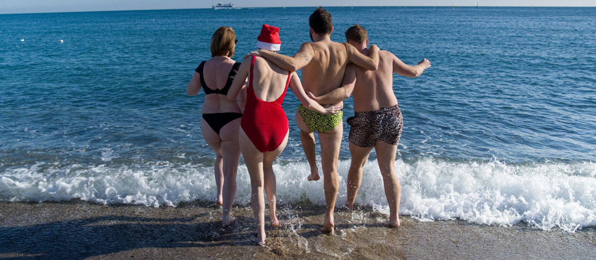 Unos jóvenes se bañan en la playa de la Barceloneta, a 25 de diciembre de 2022, en Barcelona