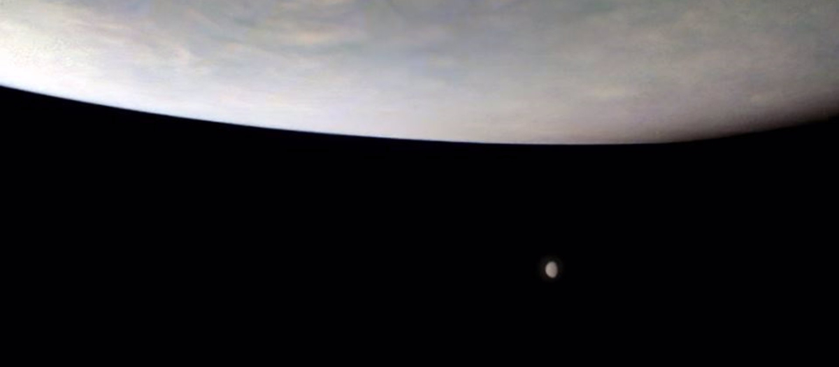 Imagen captada por la sonda Juno de dos grandes lunas en la lejanía debajo de Júpiter