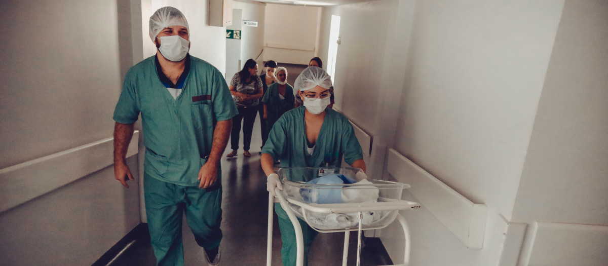 Una matrona llevando a un bebé recién nacido por un hospital