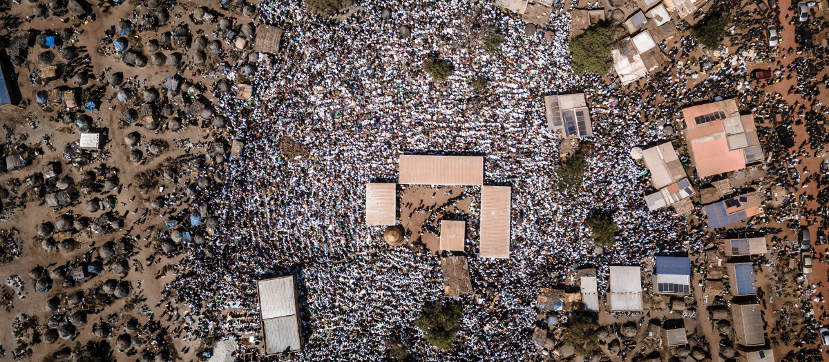 Al final del camino, una multitud de motos aparcadas hasta más allá de donde alcanza la vista; un bosque de tiendas enmarañadas y una marea de peregrinos vestidos de blanco y formando verdaderos ríos de gente entre los arbustos. Hay de todo: hombres con los pies encadenados, lisiados, desgraciados y desposeídos. Todos los que la sociedad burkinesa ya no sabe qué hacer con ellos o cómo curarlos. "Hemos probado tratamientos de todo tipo pero en vano", cuenta Awa Tiendrebeogo, familiar de un enfermo aquejado de "vértigo" recurrente. "Luego, un conocido nos habló de Adja y aquí hemos venido", explica la mujer. Las curas de Adja son gratis pero las ofrendas son bienvenidas. Por los alrededores, han ido emergiendo varias obras, financiadas por ricos donantes. Los comerciantes se olieron el filón y llenaron de puestos la carretera de acceso. Caminos y miradas convergen hacia la tienda de la curandera, que se yergue en medio de la multitud. Por los altavoces se oyen varios encantamientos. "No hay más divinidad que Dios", repiten a coro miles de fieles. Y entonces aparece Adja: una joven con trenzas vestida con un pareo y una vieja camiseta, caminando descalza y con un bastón de madera del que nunca se separa. - Heridas invisibles - Para empezar, Adja mira fijamente al sol, haciendo espasmos con la cara y luego examina a los asistentes. "Ese de ahí, con el suéter rosa, pronto tendrá un accidente", dice. "Por allá hay un hombre que ha venido a investigar sobre mí", suelta, sin aclarar de quién está hablando. El aura de la joven, según ella, provocaría celos entre sus competidores. Entre la muchedumbre, muchos son los que le desean que le vayan mal las cosas, asegura. Por la noche, en el mundo de los espíritus. esos brujos se aliarían para atacarla con maleficios. Adja muestra unas heridas, invisibles, en brazos, piernas... por todo el cuerpo. Una tortura incesante, afirma. Y, sin embargo, la reputación de la joven no deja de aumentar. Y solo han pasado tres años desde su primera cura. La curandera combina varios métodos, desde oraciones musulmanas a productos farmacéuticos tradicionales, asando por ceremonias de brujería, en un país mayoritariamente musulmán con un sistema sanitario precario y en el que las creencias tradicionales siguen muy arraigadas. Oficialmente, solo el 9% de los burkineses se declaran "animistas" pero esa proporción está muy subestimada. De los pacientes que han acudido a verla hoy, mayoritariamente musulmanes, muchos no quieren ser filmados de cerca. "Lo que se suele decir por aquí es que, de día, la gente critica la tradición pero, por la noche, la practica", comenta un ayudante de la curandera. - "Espíritus malignos" - Los casos más visibles son las víctimas de "espíritus malignos", como Fatoumata, una joven que de repente perdió el uso de las piernas. Está tumbada en el suelo, inerte, y Adja la rocía con agua "bendita" y camina lentamente sobre ella, descalza. Las oraciones del público van ganando intensidad y se mezclan con los gritos de otros "poseídos" que esperan su turno. Pero no funciona. Fatoumata no se levanta. La paciente siguiente sí que recuperará la sensibilidad en las piernas. A Adja, la fama le viene de su "transparencia". A los casos desesperados o que están fuera de su alcance, les dice sin rodeos que no puede hacer nada por ellos. "La reputación de Adja se debe a su integridad", explica Awa Tiendrebeogo. A su padre, el vértigo se le ha curado. El poder de la curandera, una especie de entidad "espiritual" que dirige su existencia y que no le autoriza libertad alguna, le prohíbe mentir, asegura. Rodeada de una legión de guardaespaldas, asistentes y biógrafos, Adja mantiene que ha renunciado a la posibilidad de tener una vida normal. Pero, cuando se aparta de la multitud, vuelve a ser Amsetou Nikiema, una joven espontánea y risueña que apenas ha dejado atrás una infancia traumática. Atormentada por las visiones que ha tenido desde siempre, Amsetou cuenta que sus familiares, que la trataban de loca y la rechazaban, solían pegarle con una cadena. "Por eso me río todo el tiempo, para poder aliviar a la gente. Como la gente me odiaba durante mi infancia, yo quería que todo el mundo me amara", explica. A quienes tanto mal le hicieron, les da las gracias: "Gracias a mi familia, gracias a los malos tratos, hoy soy alguien y sé cómo cuidar de los demás. Y si durante tu infancia no sufres, nunca lograrás tener éxito en la vida".