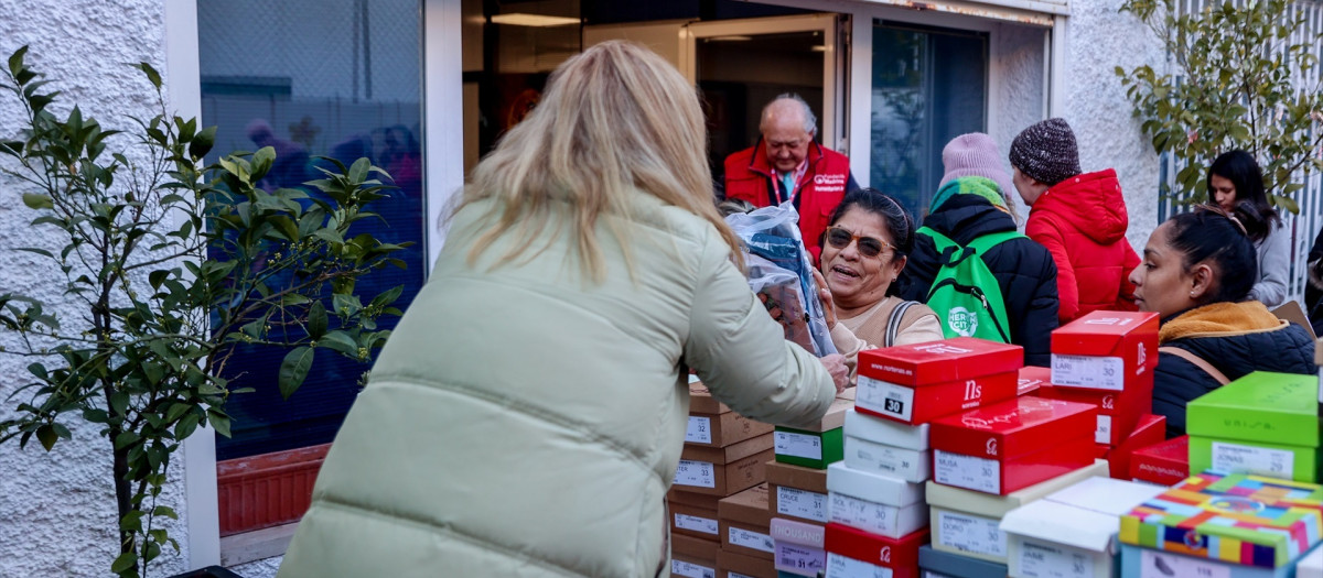 Varias personas reciben ropa de invierno y zapatos que la Fundación Madrina entrega a familias en riesgo de vulnerabilidad