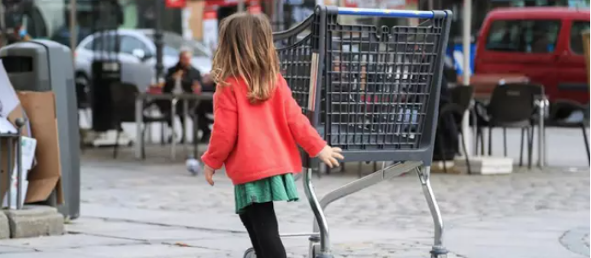 Una niña camina junto a la terraza de un bar en el centro de Madrid