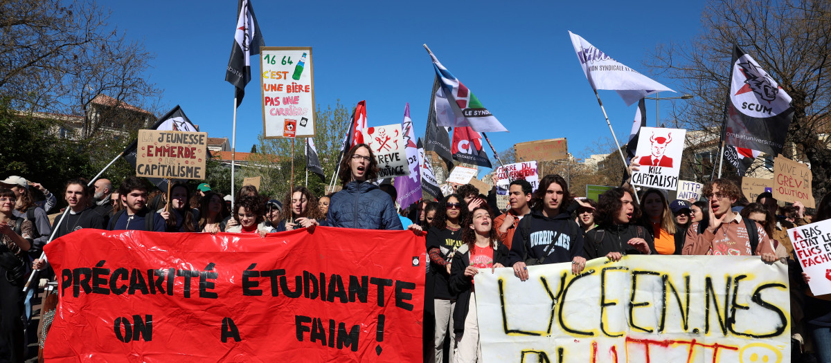 Young people hold banners that reads, ' insecurity students are hungry' (L) and 'high school students struggling' during a demonstration after the government pushed a pensions reform through parliament without a vote, using the article 49.3 of the constitution, in Montpellier, southern France, on March 28, 2023. - France faces another day of strikes and protests nearly two weeks after the president bypassed parliament to pass a pensions overhaul that is sparking turmoil in the country, with unions vowing no let-up in mass protests to get the government to back down. The day of action is the tenth such mobilisation since protests started in mid-January against the law, which esi:includes raising the retirement age from 62 to 64. (Photo by Pascal GUYOT / AFP)