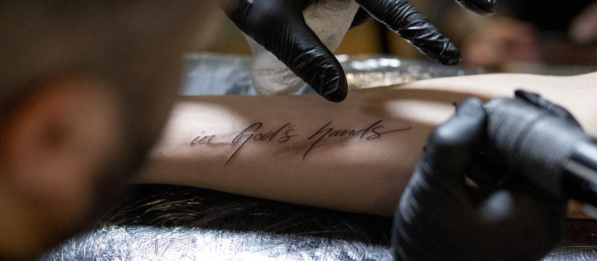 Una persona se tatúa en inglés la frase "En manos de Dios" en Viena (Austria), este sábado
