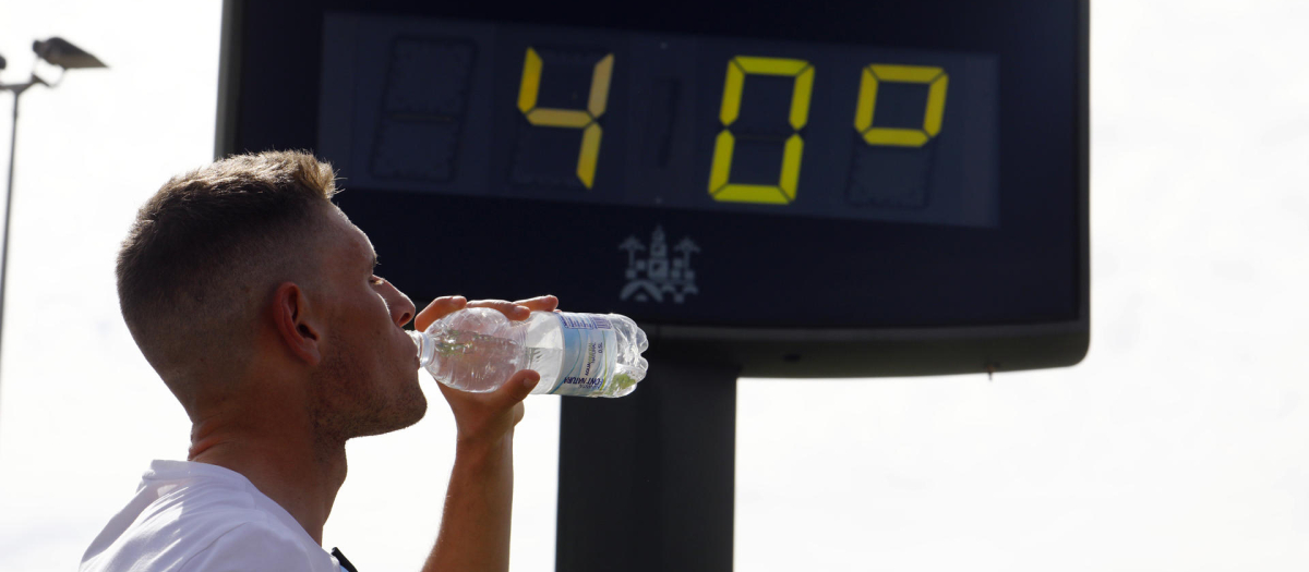 Un joven bebe agua junto a un termómetro de calle que marca 40 grados en el centro de Córdoba este pasado jueves