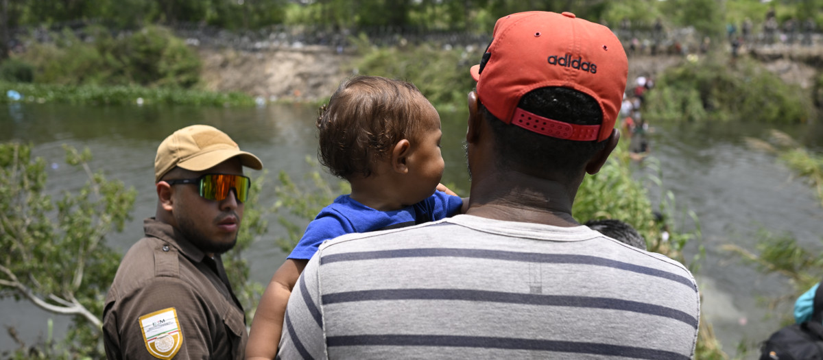 Migrants are given water by a member of the US military after they crossed into the United States from Mexico, in Brownsville, Texas, on May 11, 2023. - The US on May 11, 2023, will officially end its 40-month Covid-19 emergency, also discarding the Title 42 law, a tool that has been used to prevent millions of migrants from entering the country. (Photo by Andrew CABALLERO-REYNOLDS / AFP)