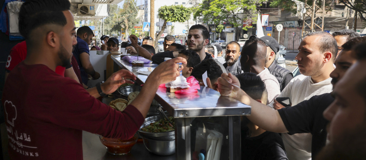 People queue at a falafel shop in Gaza city on May 14, 2023, amid a ceasefire ending five days of deadly fighting between Israel and the Palestinian Islamic Jihad militant group. A ceasefire was in effect on the Gaza Strip, drawing people back into the streets after five days of cross-border exchanges killed at least 34 Palestinians and two Israelis. (Photo by MOHAMMED ABED / AFP)