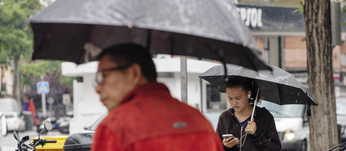 Dos personas pasean bajo la lluvia, a 23 de mayo de 2023, en Madrid